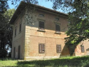 Villa rustica con tetto a spiovente e ombra di alberi mature.
