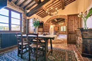 Accogliente sala da pranzo in prestigioso casale rustico con tavolo in legno e lampadario.