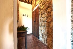 Ingresso rustico di prestigioso casale con mattoni, pietra e luce naturale.