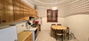 Cucina rustica con zona pranzo, mobili in legno e lampada a sospensione.