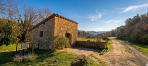 Tenuta con fonte romana e casetta in pietra su sentiero rustico.