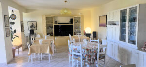 Sala da pranzo luminosa in villa storica con arredi bianchi, parco e piscina panoramica.