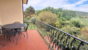 Confortevole balcone con vista boscosa, Italia. Terrazze rosse, ferro nero, cielo azzurro.