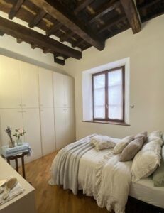 Camera da letto serena con letto bianco, travi e giardino pensile a Castelnuovo di Garfagnana.