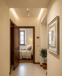 Corridoio crema con luci soffuse porta a camera da letto in prestigioso appartamento a Castelnuovo di Garfagnana.
