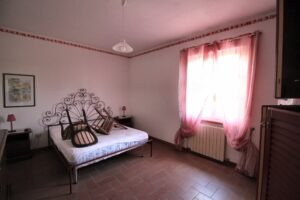Camera da letto singola con letto metallo, comodini neri, lampade rosse e tende rosa.
