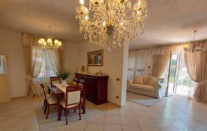 Un ampio e luminoso living e approdo con toni neutri e legno scuro, accentuato da finestre a tende beige.
