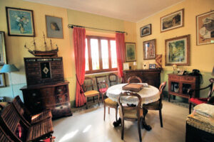 Sala da pranzo elegante con tavolo rotondo, mobili antichi e tende rosse