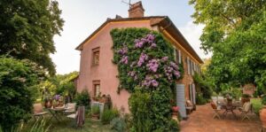 Casale toscano con parco e patio vicino Firenze: facciata pesca, edera viola e giardino curato.