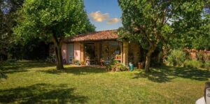 Casale toscano con parco e piscina vicino Firenze: tetto rosso, alberi e patio accogliente.