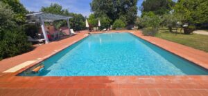 Piscina blu in casale toscano con parco e piscina vicino Firenze, sdraio e prato sereno.