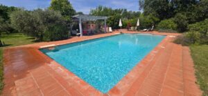 Piscina turchese in casale toscano con parco e piscina vicino Firenze, relax tra verde e cielo.