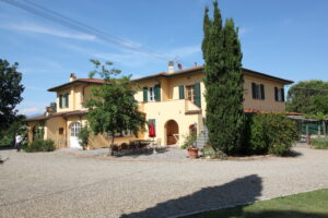 Villa toscana con persiane verdi, cortile in ghiaia e cipresso