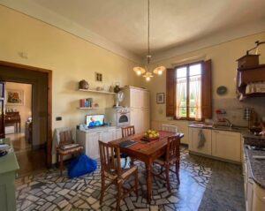 Cucina gialla accogliente con tavolo da pranzo, angolo cottura e scrivania con monitor.