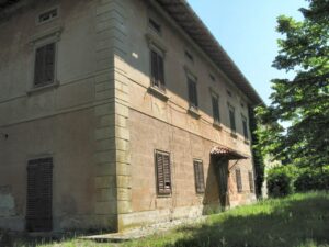Vecchia villa in stile rustico su pendio, riarsa dal sole, con mattoni eintonaco.