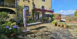 Villa gialla con balcone fiorito e patio, appartamento ristrutturato con giardino pensile a Castelnuovo di Garfagnana.