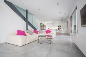 Soggiorno moderno e luminoso con divano modulare bianco, cucina a vista e dettagli di design.