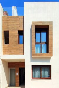 Facciata moderna con rivestimenti in legno e intonaco bianco sotto un cielo blu.