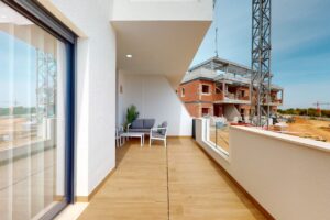 Terrazzo moderno arredato con divano, poltrone, piante e vista su cantiere edile.