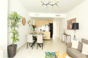 Interniente moderno open space con soggiorno, zona pranzo e cucina in toni neutri.