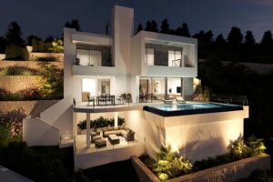 Villa moderna ed elegante illuminata di notte su una collina terrazzata con piscina a sfioro.
