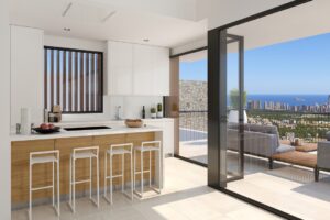 Cucina moderna e luminosa con isola, affaccio su terrazza e vista panoramica sul mare.