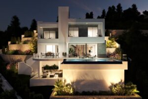 Villa moderna illuminata di notte su una collina con piscina a sfioro e terrazze.