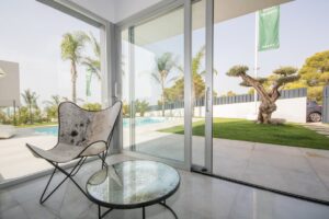 Intern moderno con poltrona di design, grandi vetrate e vista sulla piscina e sul giardino.