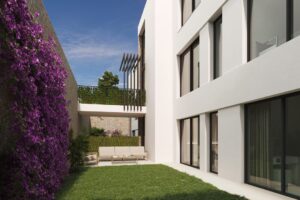Cortile moderno di un condominio di lusso con prato verde, balcone e bouganville viola.