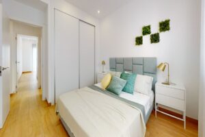 Camera da letto contemporanea luminosa con letto imbottito, pareti bianche e grandi tende trasparenti.