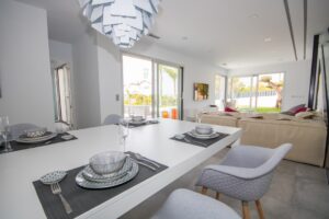 Soggiorno open space moderno con zona pranzo elegante, grandi vetrate e vista sul giardino.