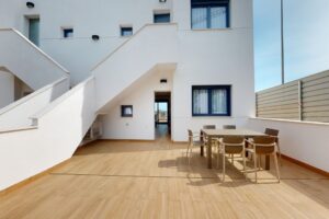 Terrazzo in legno moderno di una casa bianca con tavolo da pranzo e scala.